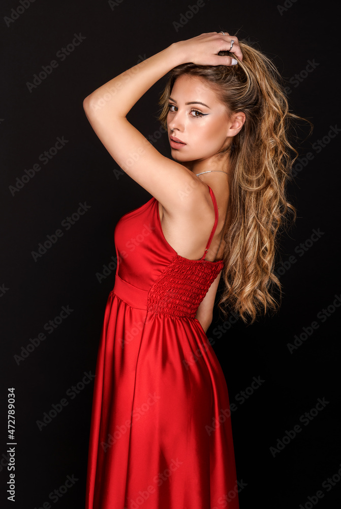 Elegant female in red dress standing against black background Elegant female in red dress standing against black background