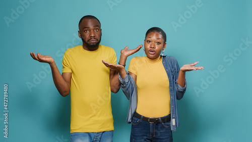 Tableau sur toile Uncertain people raising shoulders and not knowing to answer question in studio