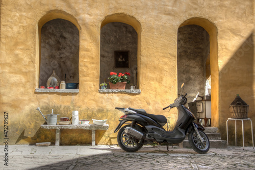 Istria, Croatia - View of a scooter parked in front of an old yellow house in the ancient town of Oprtalj
