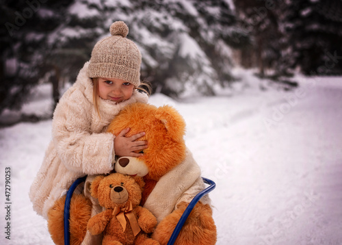 girl with a toy. little girl with a toy. A girl with a teddy bear sledding in a snowy forest. Winter fun. Winter holidays. 