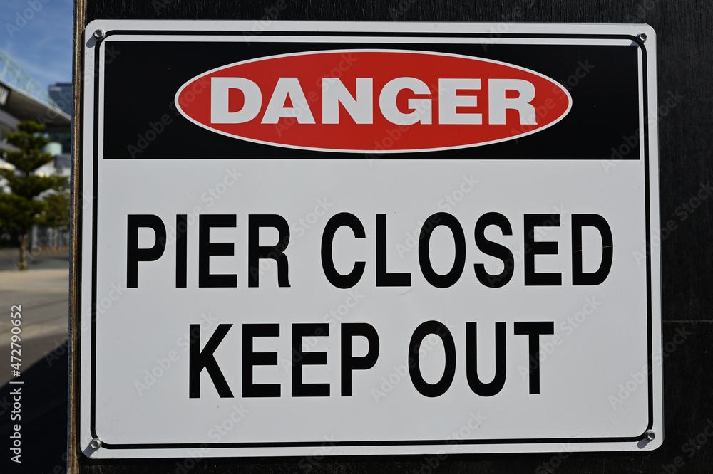 Fototapeta premium A danger sign warning people to keep out of the closed pier