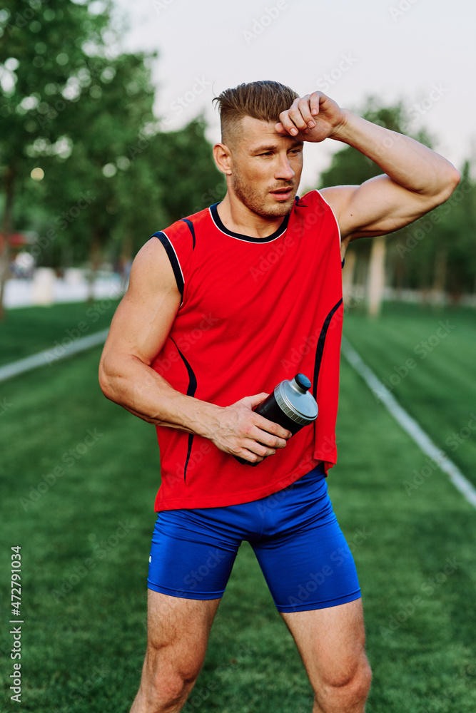 Fototapeta premium Cheerful sporty man in the park on green grass doing exercises