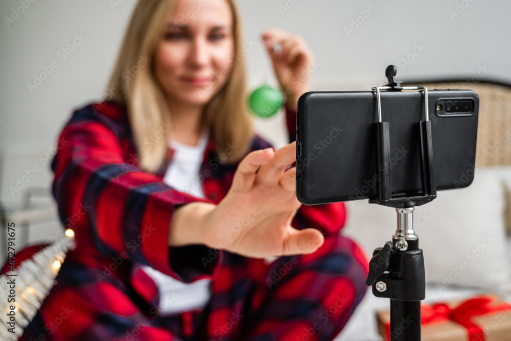 A beautiful blonde in red pajamas sets up her phone to video chat with her family and friends for the Christmas and New Year celebrations. Video call A beautiful blonde in red pajamas sets up her phone to video chat with her family and friends for the Christmas and New Year celebrations. Video call