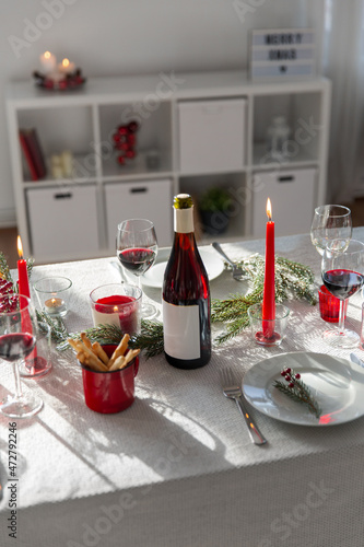 winter holidays, dinner party and celebration concept - christmas table serving with candles, crockery and wine at home