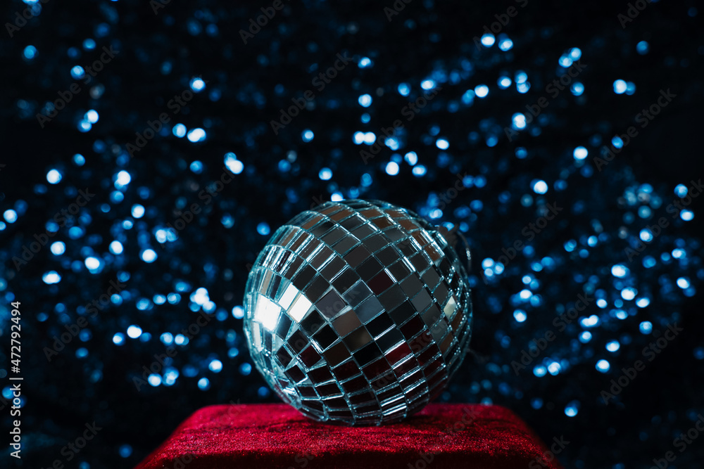 Obraz premium disco ball on red velvet podium on blue sequin background