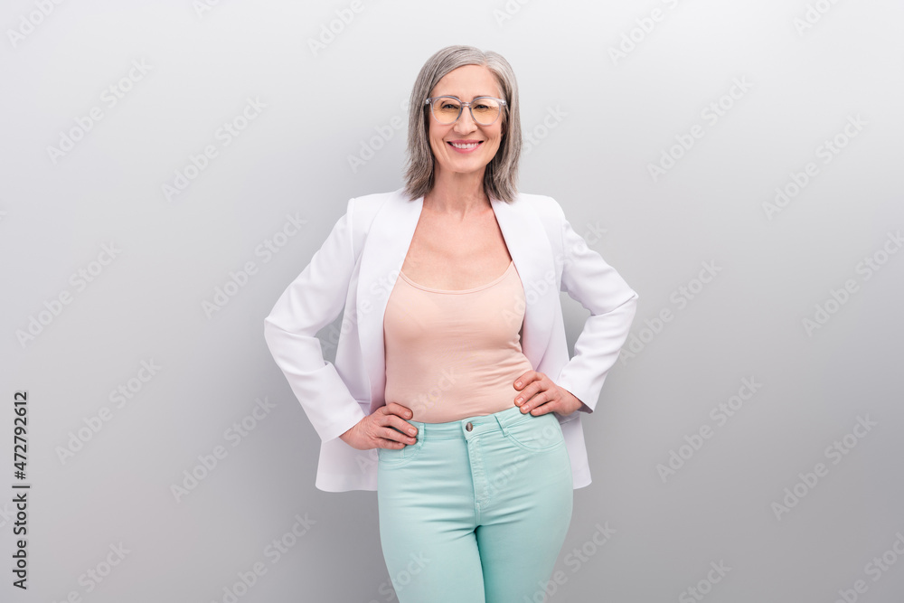 Photo of nice white hairdo old teacher lady wear spectacles jacket pants smart casual isolated on grey color background Photo of nice white hairdo old teacher lady wear spectacles jacket pants smart casual isolated on grey color background