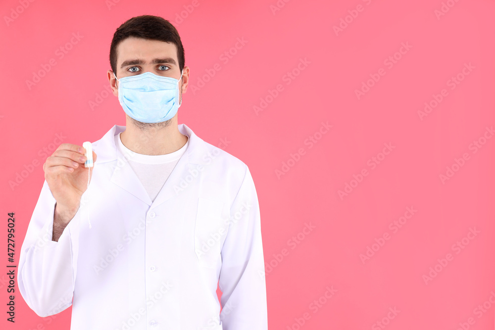 Doctor intern holds tampon on pink background Doctor intern holds tampon on pink background