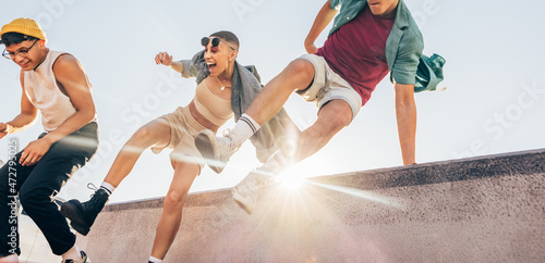Energetic friends jumping over a wall outdoors