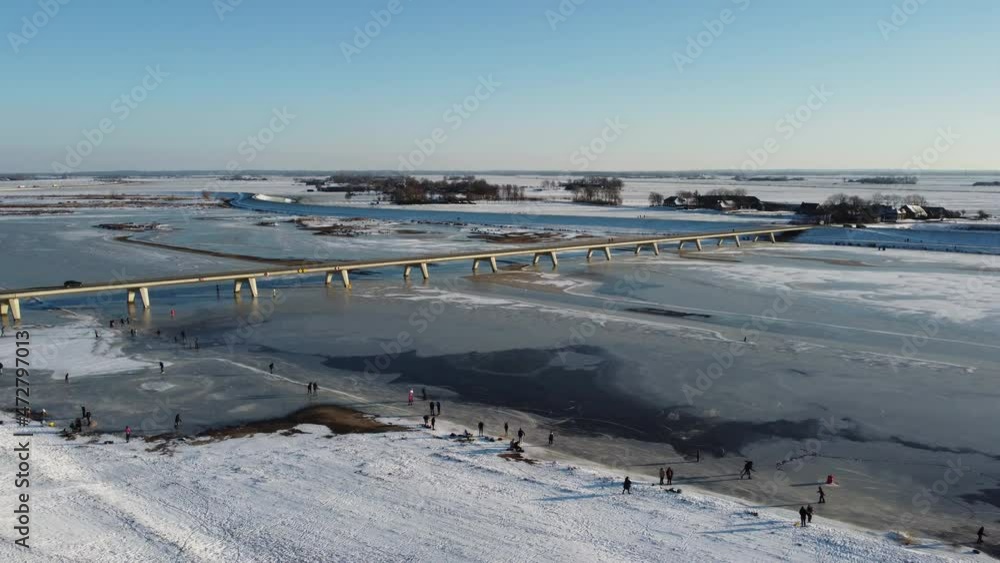 Ice skating people on a frozen Reevediep lake during a beautiful winter day in Overijssel, The Netherlands. Aerial drone point of view. Ice skating people on a frozen Reevediep lake during a beautiful winter day in Overijssel, The Netherlands. Aerial drone point of view.