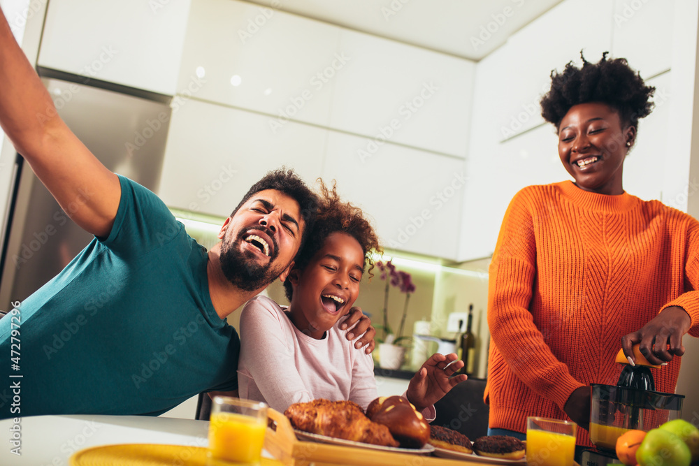 Family at home eating breakfast in kitchen together, having fun.