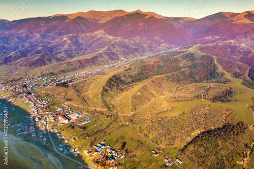 Top view of the colorful slopes of the mountains on an autumn sunny day. Panoramic view of the town of Kolochava in the mountain valley. Carpathians, Ukraine photo