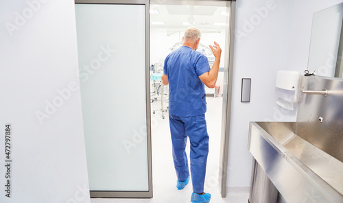 Surgeon after washing hands enters the operating room