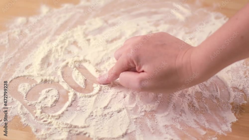 Writing the word 'Baking' with flour on the wooden board. Bakery or making bread at home Writing the word 'Baking' with flour on the wooden board. Bakery or making bread at home