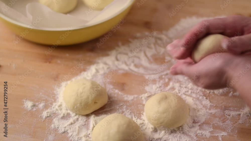 Shaping round yeast buns. Woman is rolling the dough between her hands above the table with flour. Baking at home Shaping round yeast buns. Woman is rolling the dough between her hands above the table with flour. Baking at home