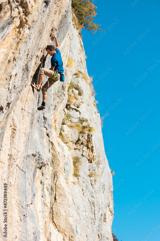 A strong man climbs a rock