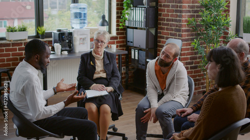 Multi ethnic people having discussion about addiction at aa group therapy in circle. Patients talking about mental health problems with psychiatrist at rehabilitation program meeting