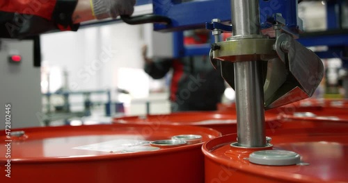 Machine oil production plant. Red metal barrel move along the conveyor line to dispense engine oil. Development, storage and supply of lubricants for industrial enterprises. Shot with RED camera.