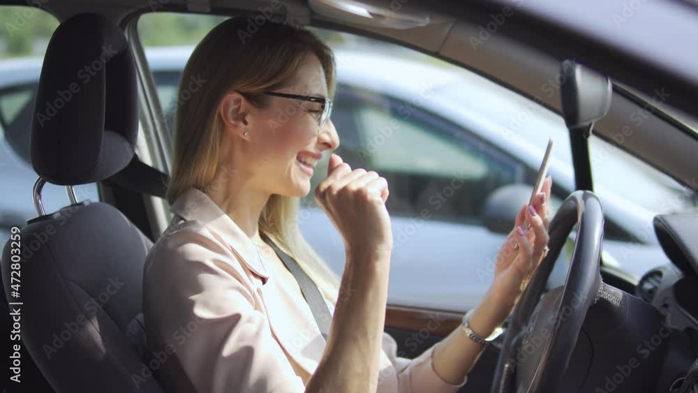 Cheerful lady using mobile app on smartphone sitting in car, happy with cashback Cheerful lady using mobile app on smartphone sitting in car, happy with cashback
