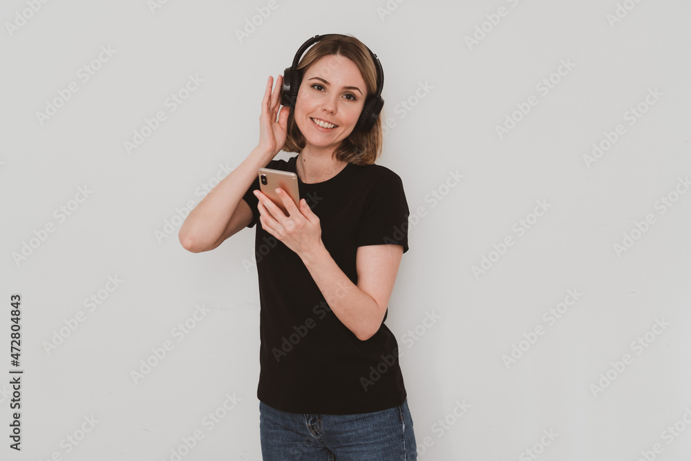 charming European woman in casual clothes with headphones listening to music on smartphone on white background charming European woman in casual clothes with headphones listening to music on smartphone on white background