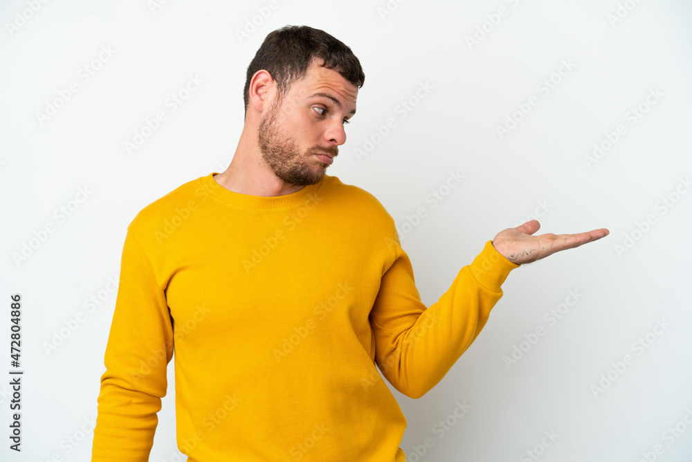 Young Brazilian man isolated on white background holding copyspace with doubts Young Brazilian man isolated on white background holding copyspace with doubts