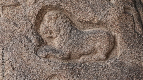 Lion sculpture carved in rock. The rock is located in the background