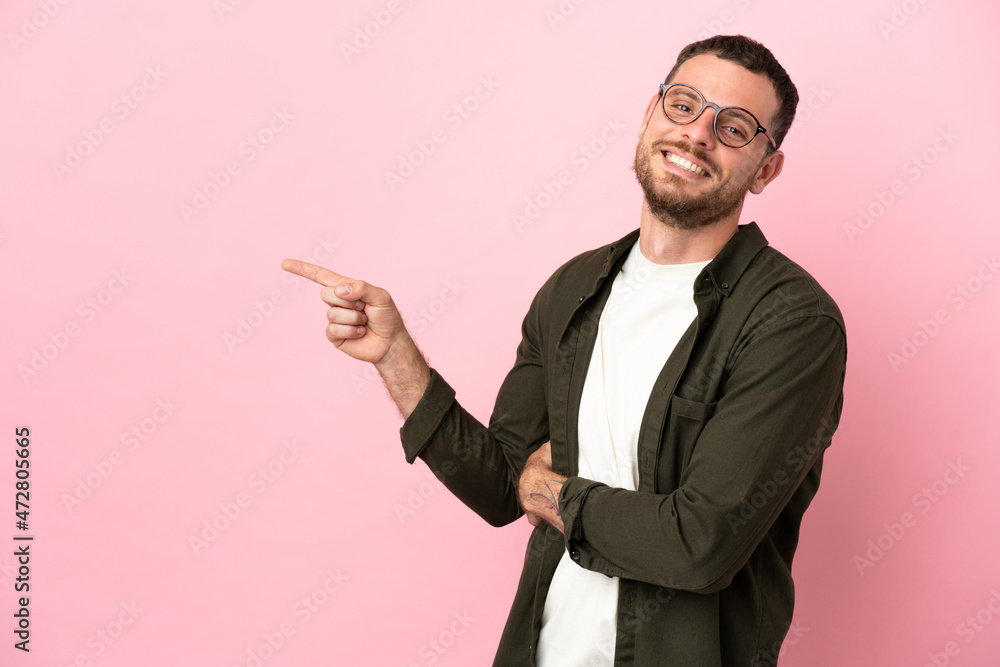 Young Brazilian man isolated on pink background pointing finger to the side Young Brazilian man isolated on pink background pointing finger to the side