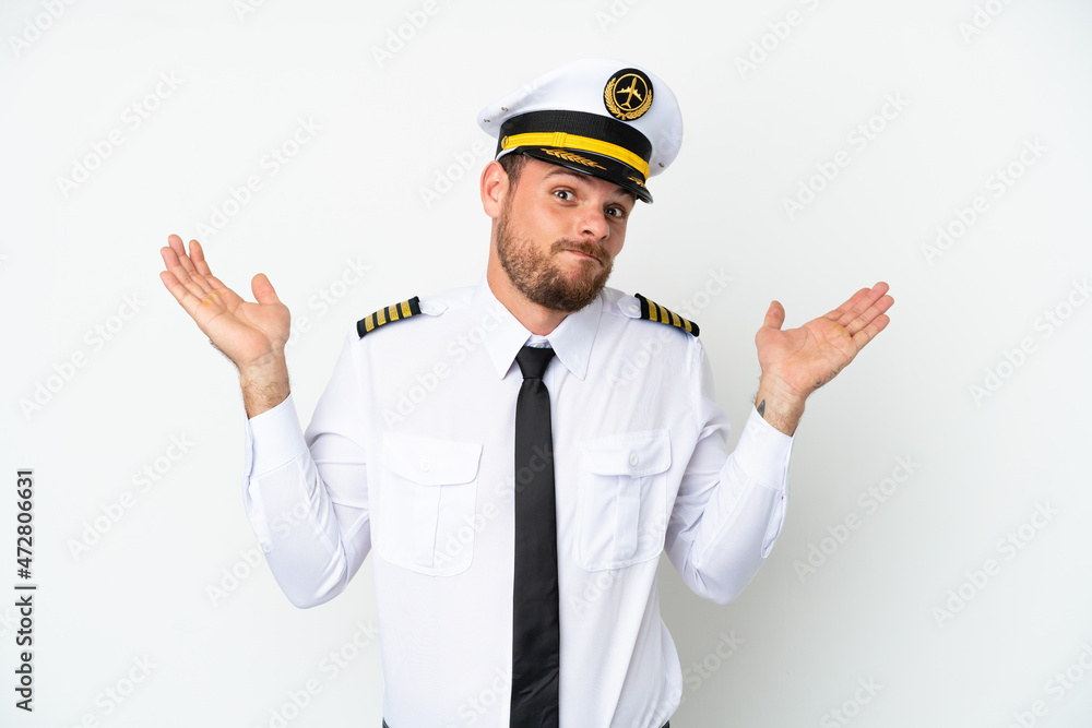 Airplane Brazilian pilot isolated on white background having doubts while raising hands Airplane Brazilian pilot isolated on white background having doubts while raising hands