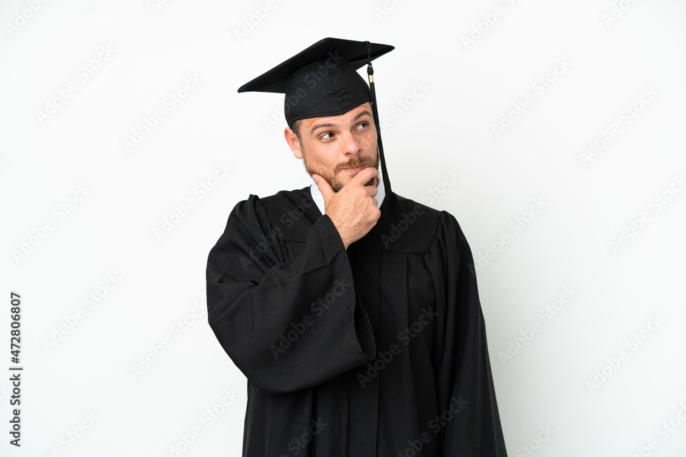 Young university Brazilian graduate isolated on white background and looking up Young university Brazilian graduate isolated on white background and looking up