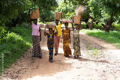 Group of smiling black African girls carrying their goods to the weekly village market