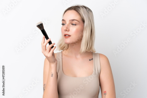 Young caucasian woman isolated on white background holding makeup brush