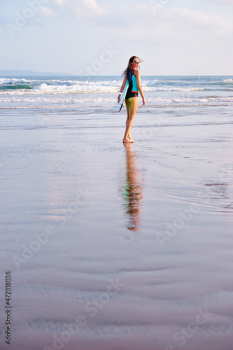 Hobby and vacation. Holiday on the beach. Pretty young woman carrying surf board.
