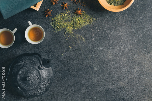 Top studio shot of a still life with vintage black metal Japanese tea pot on a dark stone table. Free copy space for caption. Tea ceremony concept. Hot beverage preparation. Green tea and anise star.