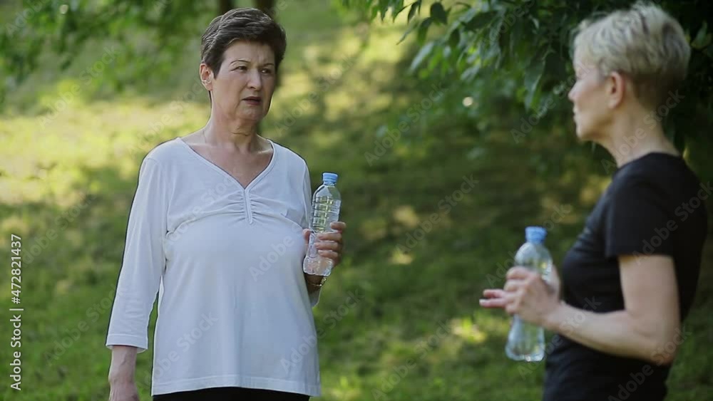 Cheerful senior women talking and holding a bottle of water Cheerful senior women talking and holding a bottle of water