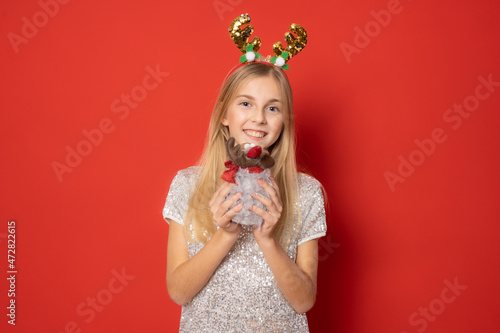 Beautiful little girl wearing Santa hat for Christmas isolated on red background.