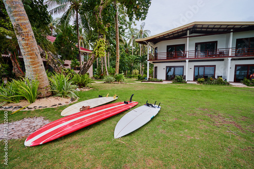 Tropical villa with surf boards on the grass. © luengo_ua