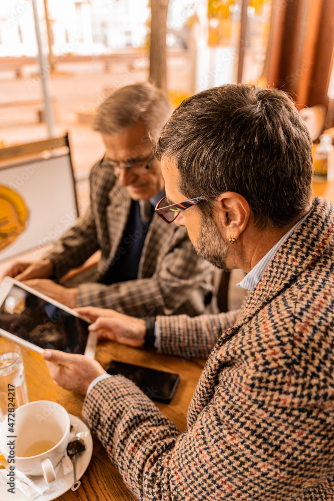 Discussing the documetns together while trying to unlock the tablet in the cafe Discussing the documetns together while trying to unlock the tablet in the cafe