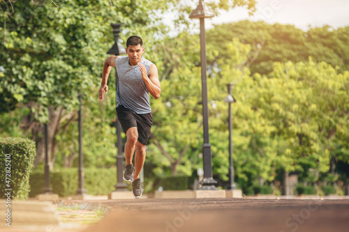 Silhouette of young man running sprinting on road. Fit runner fitness runner during outdoor workout with sunset background.