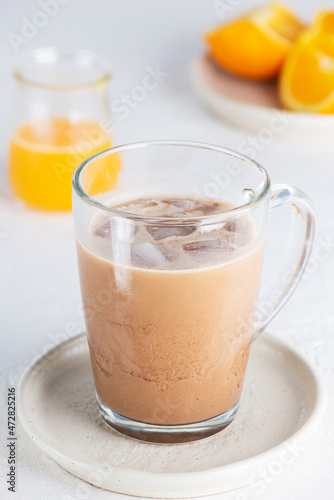 Cold vegan moccacino coffee with chocolate and orange juice in a glass mug.