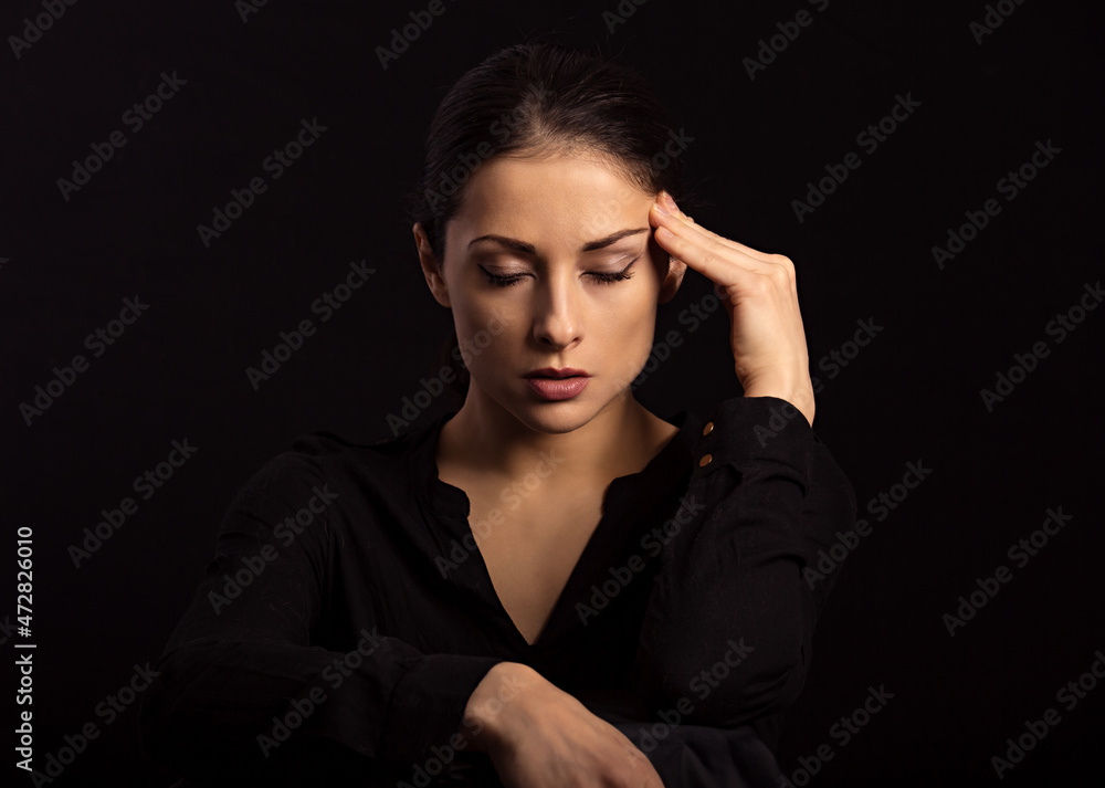 Business strong thinking woman find the answer in clever mind with closed eyes with fingers near the face in black t-shirt on dark shadow black background. Closeup front view Business strong thinking woman find the answer in clever mind with closed eyes with fingers near the face in black t-shirt on dark shadow black background. Closeup front view