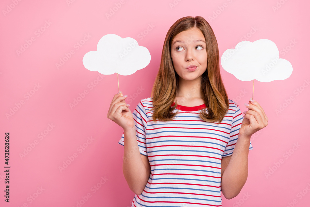 Photo of unsure small brown hairdo girl hold clouds look empty space wear striped t-shirt isolated on pink color background Photo of unsure small brown hairdo girl hold clouds look empty space wear striped t-shirt isolated on pink color background