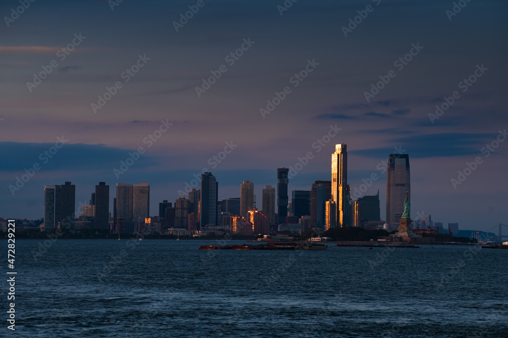 Fototapeta premium Travel to New York. Sunset over the skyline of Manhattan, one of the most touristic cities in the world. Amazing view to its skyscraper tall office buildings.