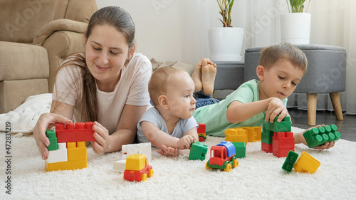 Smiling cheerful baby  boy and mother palying toys on carpet at home. Concept of family having time together and children development