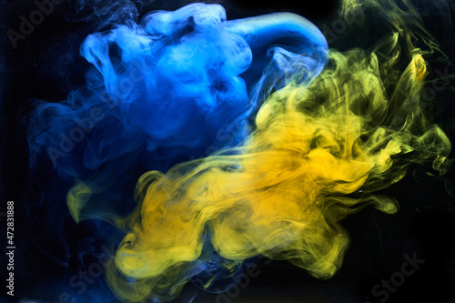 Blue yellow smoke on black ink background, colorful fog, abstract swirling ocean sea, acrylic paint pigment underwater