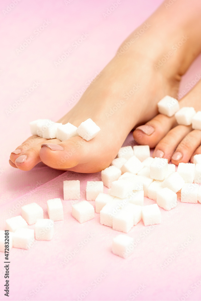 Sugar cubes lying in a row on female feet on pink background with copy space, depilation concept Sugar cubes lying in a row on female feet on pink background with copy space, depilation concept