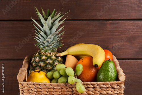 Fototapeta Naklejka Na Ścianę i Meble -  Mix of fresh juicy colorful exotic tropical fruits in basket on wooden background