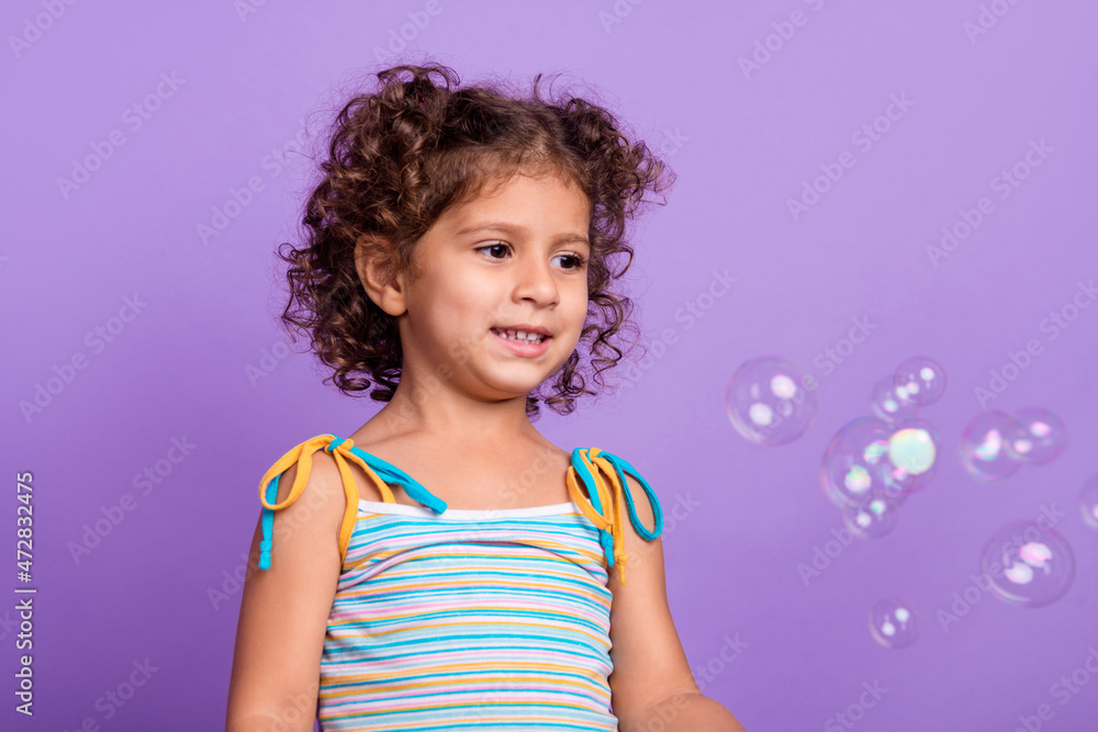 Photo of funky little brunette girl look bubbles wear striped top isolated on violet color background Photo of funky little brunette girl look bubbles wear striped top isolated on violet color background