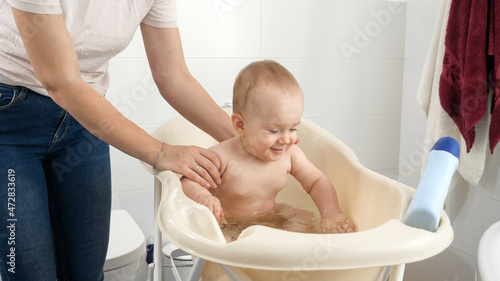 Happy smiling baby boy having bath and fun in bathroom