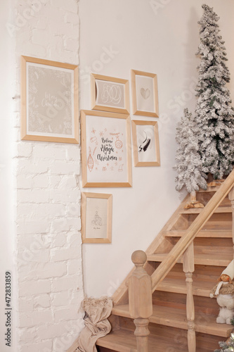 christmas tree and frames with pictures on the wall by the staircase