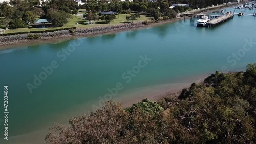 Drone aerial pan up over park and blue water harbour on a sunny day photo