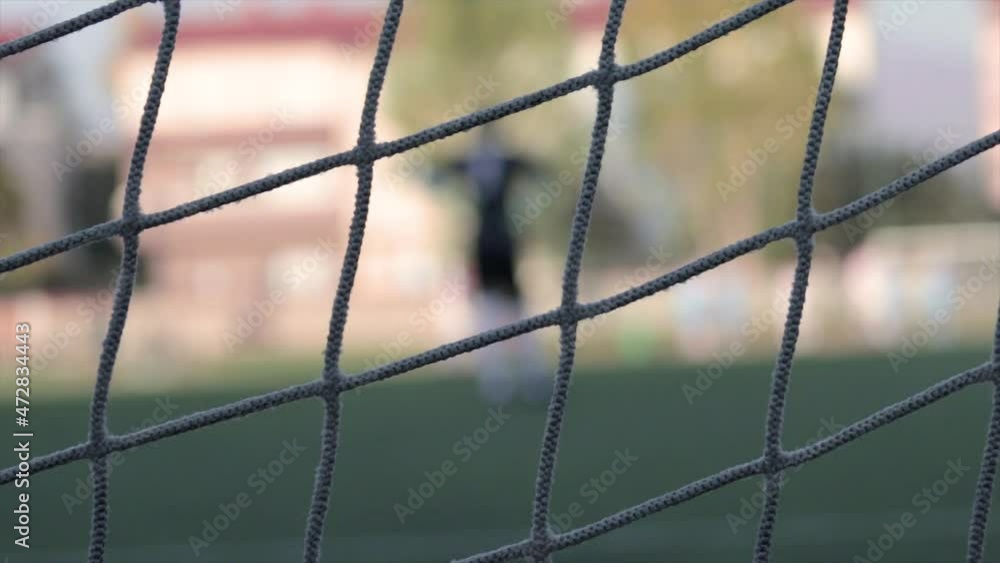 Football net with the goal keeper blurred out in the background. Football net with the goal keeper blurred out in the background.